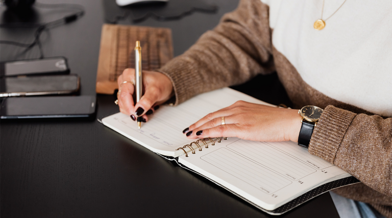 A person filling out their day planning calendar with social events.