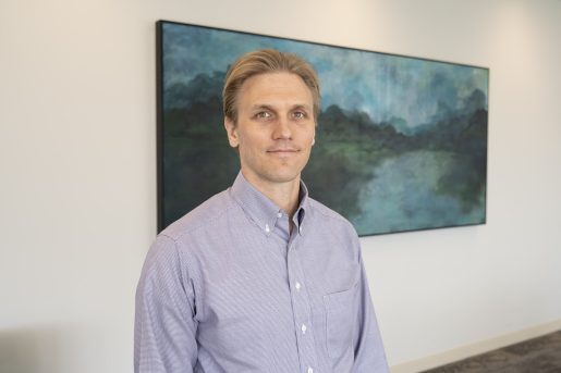 Patient Zach Wawrzgnack standing in front of a painting in the McNair Building at Baylor Medicine.